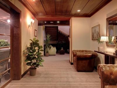 Accogliente hall d'hotel con poltrone in pelle, piante ed elementi in legno con luce calda.