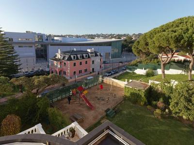 Vista di un'area giochi accanto a un edificio rosa e alberi in una zona alberghiera.