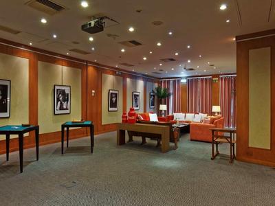 Salone elegante con tavoli, moquette, opere d'arte alle pareti e divani sullo sfondo.