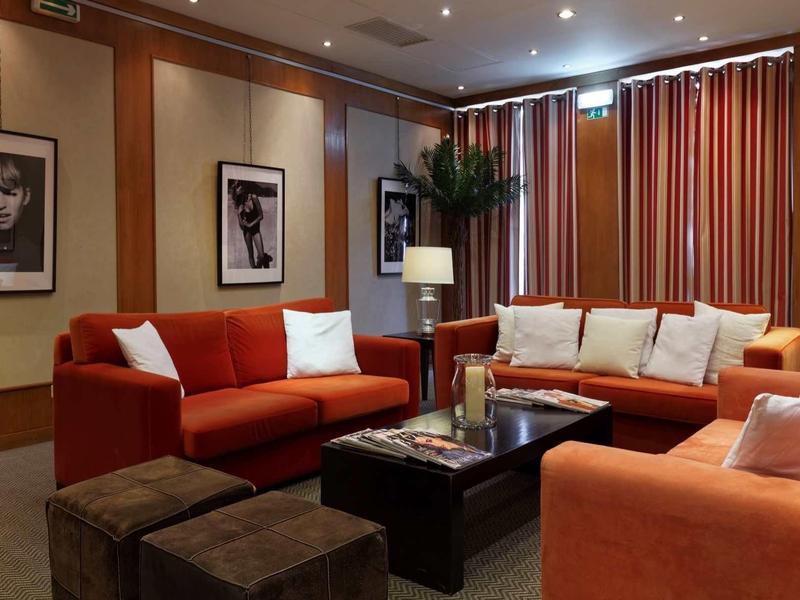 Soggiorno moderno con divani arancioni, tavolino e illuminazione soffusa in un hotel.