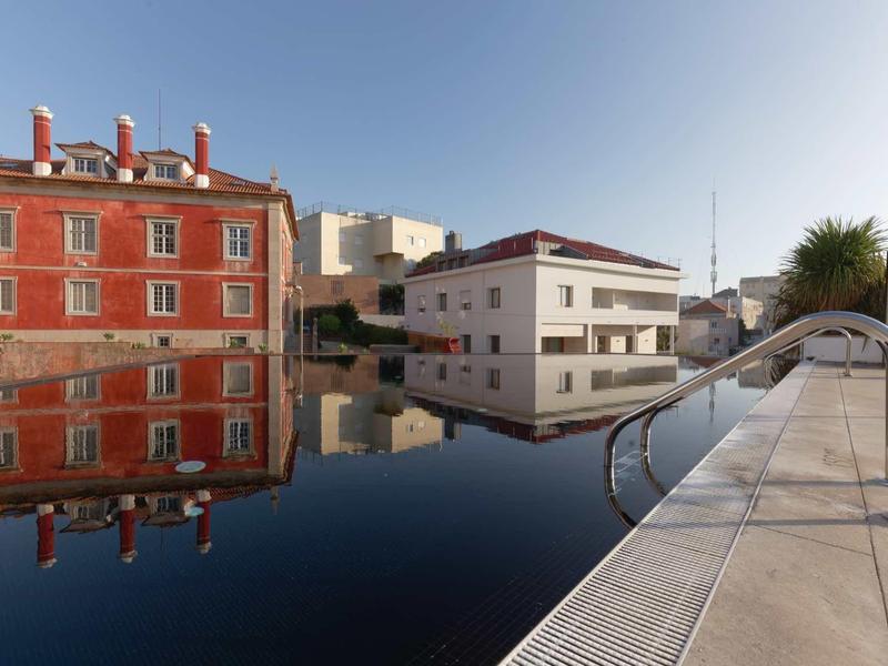 Piscina moderna accanto a edifici storici e moderni sotto un cielo sereno