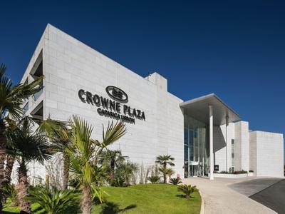 Modern white hotel entrance with clear Crowne Plaza signage and palm trees
