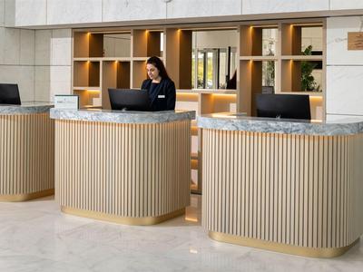 Modern hotel lobby with three reception desks and a female receptionist