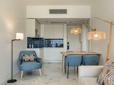 Modern furnished living area with open kitchen, seating, and lighting fixtures.