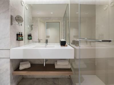Modern bathroom with white sink, mirror, and glass shower in a bright design.