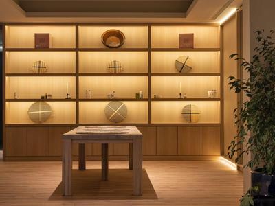 Modern, warmly lit shelves with decorations and a central wooden table.