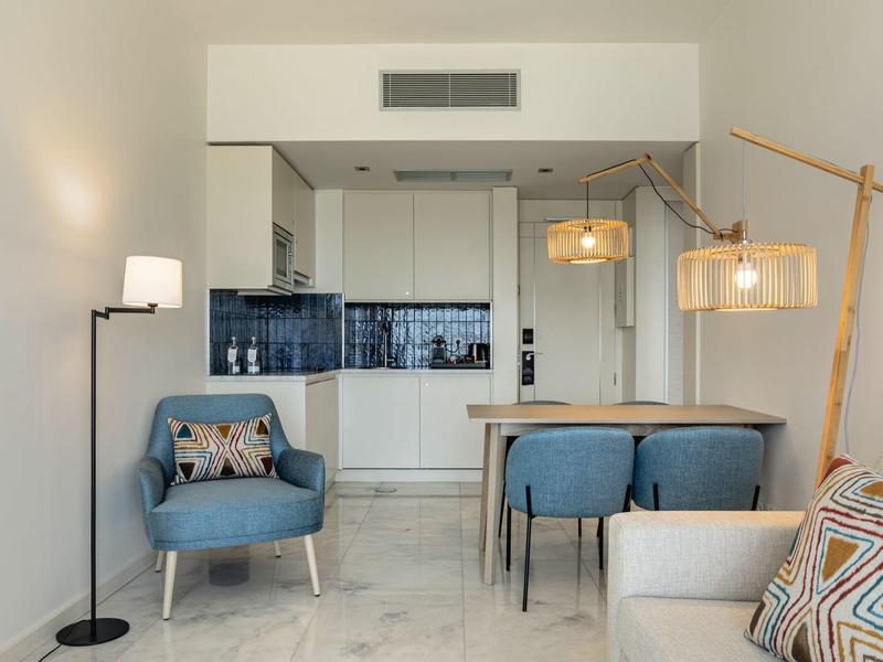 Modern furnished living area with open kitchen, seating, and lighting fixtures.