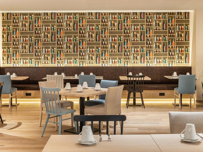 Modern breakfast room with wooden furniture and colorful wall art in a hotel.