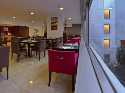 Moderner Hotel-Loungebereich mit bequemen Stühlen und großem Fenster mit Blick auf Innenhof.