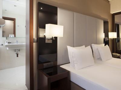 Modern hotel room with double bed, mirror, and adjoining bathroom.
