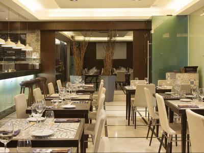 Modern eingerichtetes Restaurant mit weißen Stühlen und elegant gedeckten Tischen.