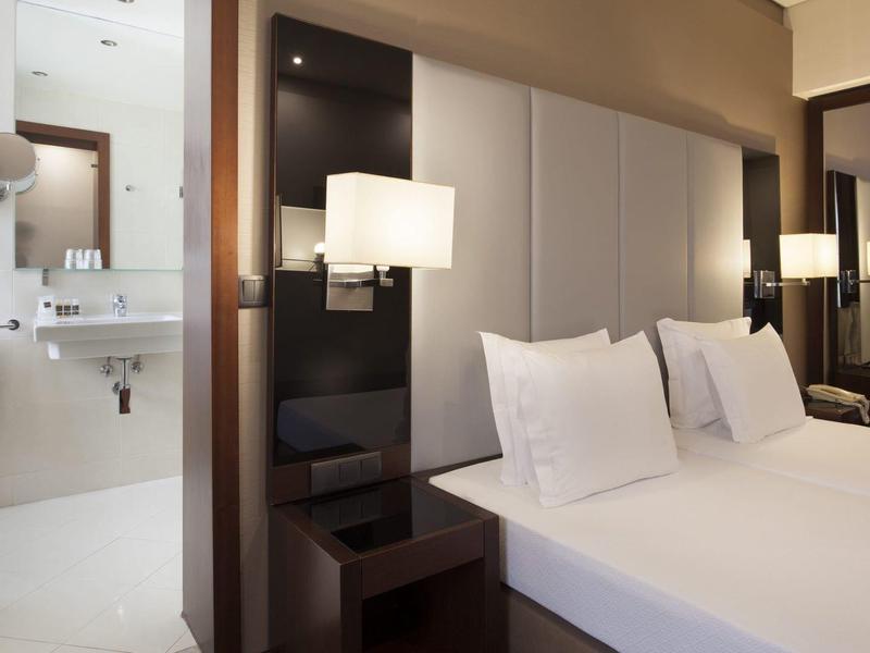 Modern hotel room with double bed, mirror, and adjoining bathroom.