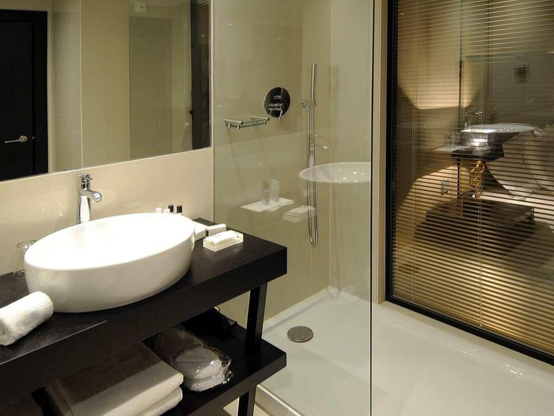Modern bathroom with freestanding white sink and glass shower in hotel room
