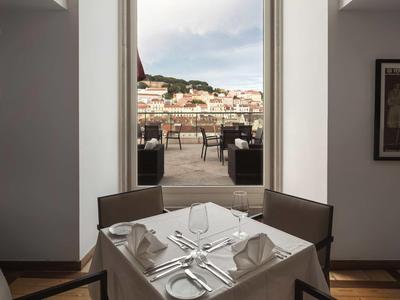 Moderner Essbereich mit eingedecktem Tisch vor großer Fensteröffnung und Stadtblick.