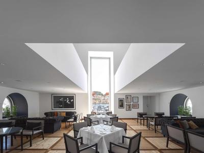 Modernes, helles Restaurant mit weißen Wänden, großen Fenstern und eleganten Holzmöbeln.