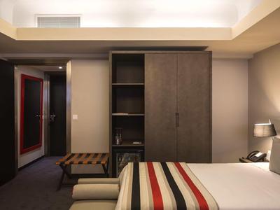 Modernes Hotelzimmer mit zwei Einzelbetten, Teppichboden und einem Kleiderschrank aus Holz.