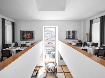 Moderner heller Speisesaal mit weißem Interieur, Tischen, Stühlen und großen Fenstern, viel Tageslicht.