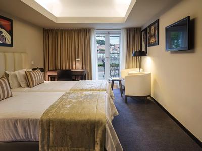 Modernes Hotelzimmer mit Doppelbett, Schreibtisch, Sessel und Balkon mit Ausblick.