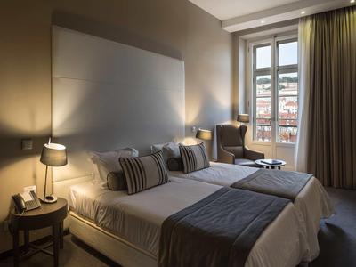 Gemütliches Hotelzimmer mit zwei Betten, Nachttischlampen und großem Fenster mit Blick auf Stadt.