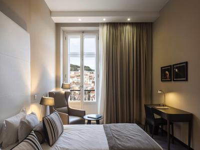 Modernes Schlafzimmer mit zwei Einzelbetten, großem Fenster, Schreibtisch und gedämpfter Beleuchtung.