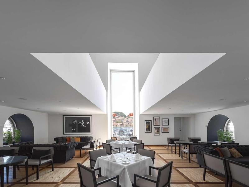 Modernes, helles Restaurant mit weißen Wänden, großen Fenstern und eleganten Holzmöbeln.