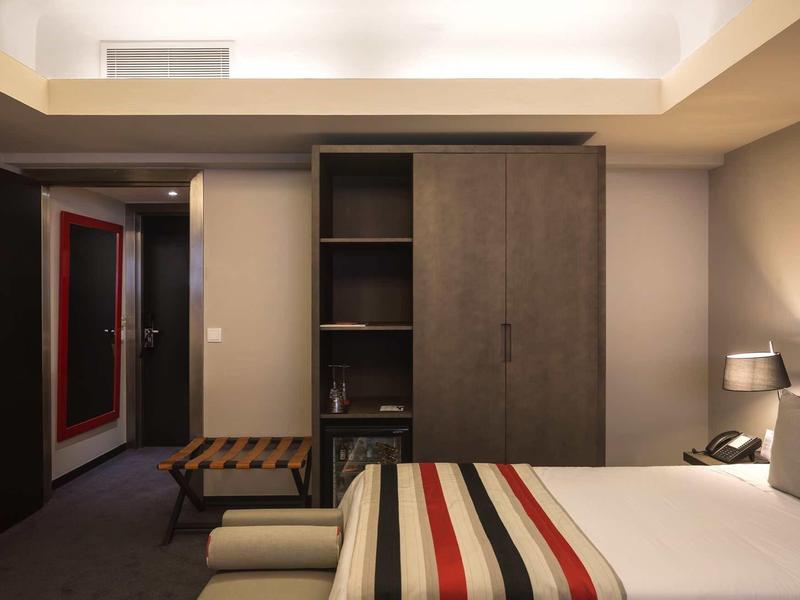 Modernes Hotelzimmer mit zwei Einzelbetten, Teppichboden und einem Kleiderschrank aus Holz.