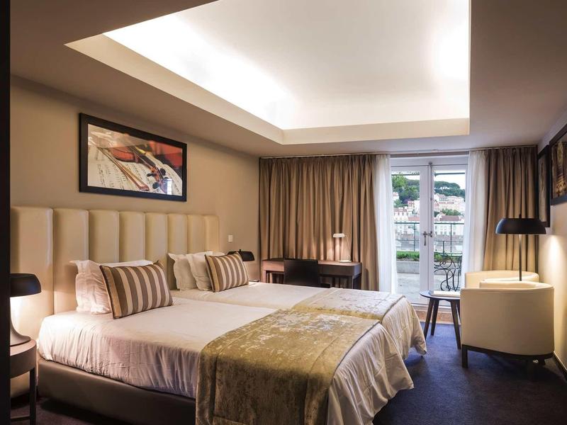 Modernes Schlafzimmer mit Doppelbett, Deckenbeleuchtung, großem Fenster und warmen Farben.