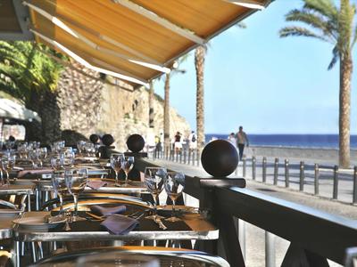 Leeg buitenterras van een café aan zee met zonnescherm en palmbomen