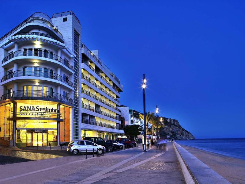 Modern hotelgebouw aan een kustpromenade bij schemering met zeezicht.