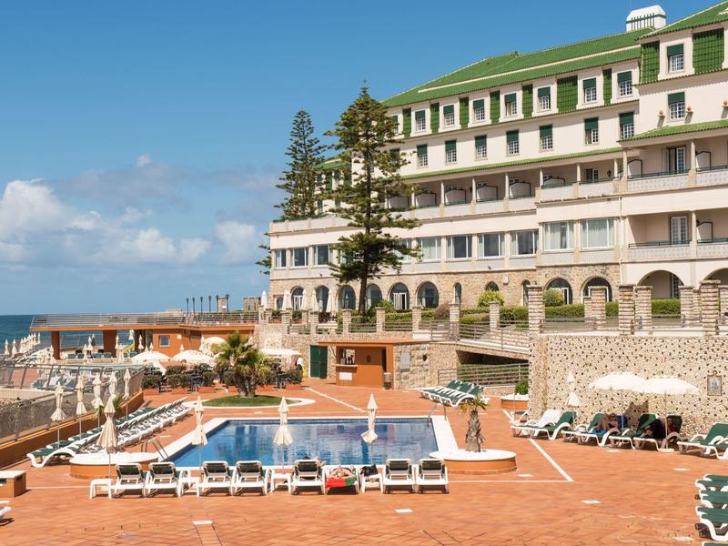 Velký hotelový komplex s venkovním bazénem a lehátky u moře.