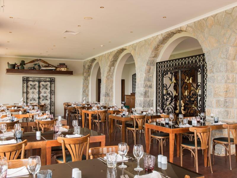 Elegantní jídelna s dřevěnými stoly, kamennými zdmi a tradiční výzdobou.