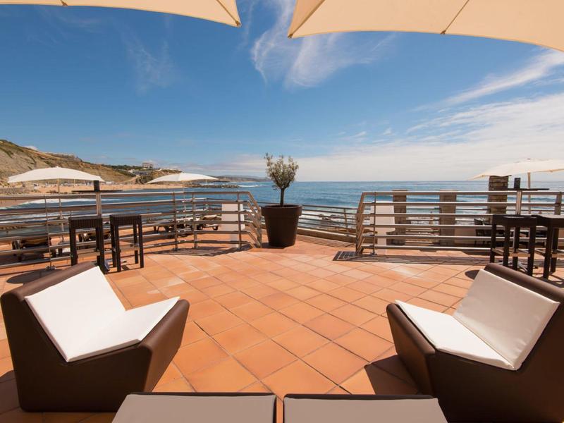 Slunečná terasa s křesly a panoramatickým výhledem na moře.