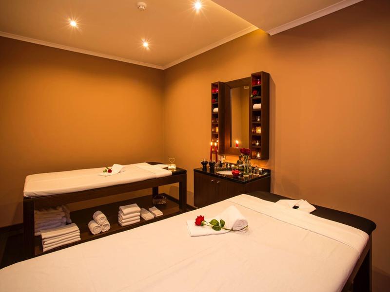 Masážní místnost s lehátkem, ručníky, zrcadlem a útulnou atmosférou.