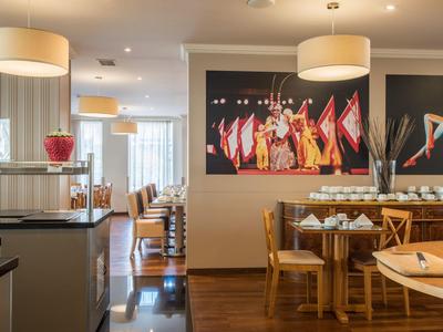 Restaurante luminoso con mesas y sillas de madera, grandes lámparas y arte decorativo en la pared.