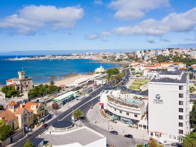 Vista panorámica de una ciudad costera con edificios, carretera principal y mar al fondo.