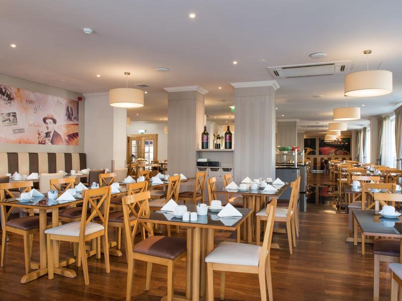 Restaurante moderno con mesas y sillas de madera, bien iluminado y decorado para los clientes.