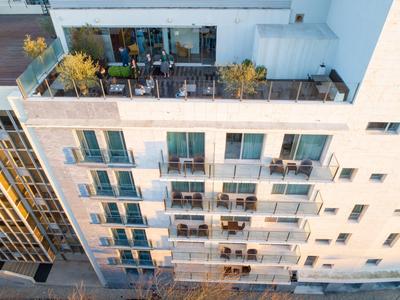 Vista di un moderno edificio residenziale con balconi e terrazze sul tetto piantumate alla luce del giorno.