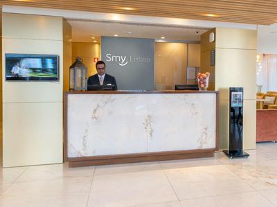 Reception dell'hotel con personale dietro un bancone in marmo e un distributore d'acqua.