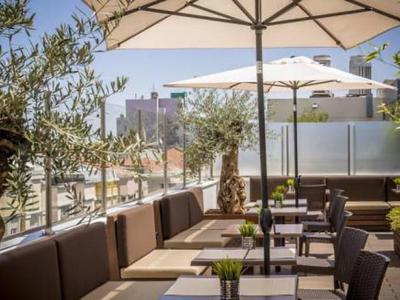 Moderna terrazza esterna con area salotto, ombrelloni e vista sulla città in un hotel.