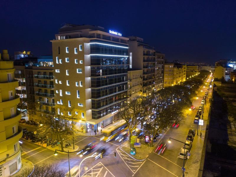Edificio di hotel moderno con finestre illuminate su una strada trafficata di notte