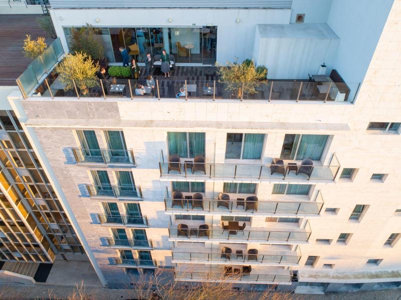Vista di un moderno edificio residenziale con balconi e terrazze sul tetto piantumate alla luce del giorno.