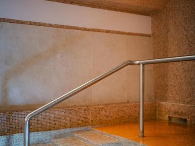 Innenbereich mit Boden aus Steinen, Wasserbecken und Edelstahlgeländer unter hellem Deckenspotlicht.