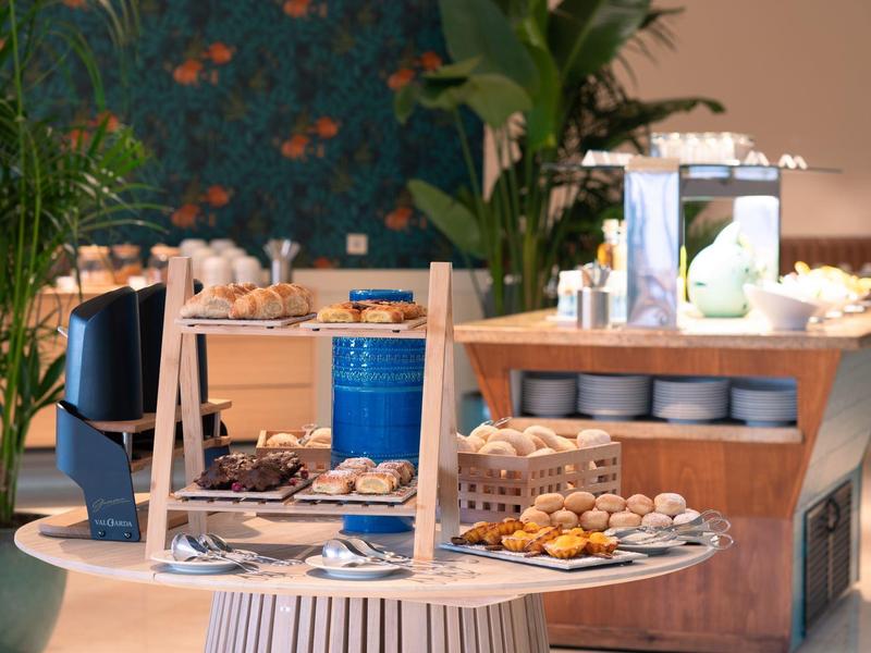 Buffet mit verschiedenen Backwaren und kleinen Snacks auf runden Tellern in modernem Raum.