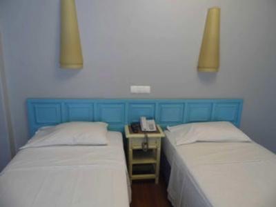 Due letti singoli con lenzuola bianche e testata blu, comodino con telefono tra di loro.