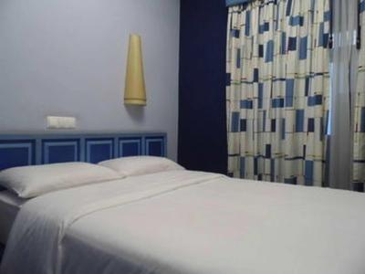 Una camera d'albergo semplicemente arredata con un letto, tende e una lampada da parete.