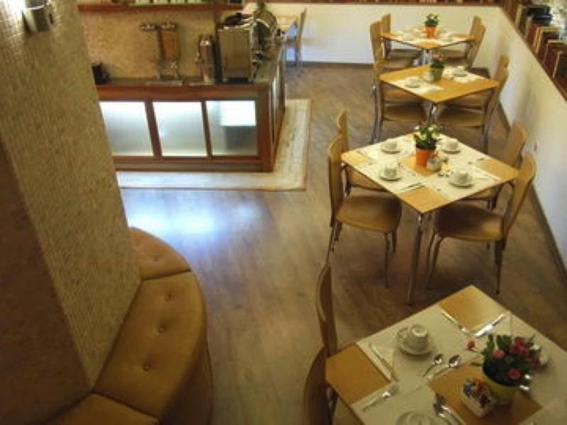 Accogliente zona pranzo con pavimenti in legno, tavoli rotondi e quadrati in un hotel.