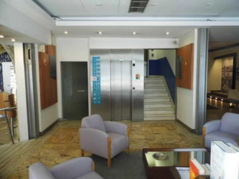 Area della hall con ascensore, posti a sedere e scale sullo sfondo.