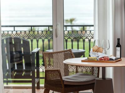 Okrągły stół z wiklinowymi krzesłami przy drzwiach balkonowych z widokiem na morze.