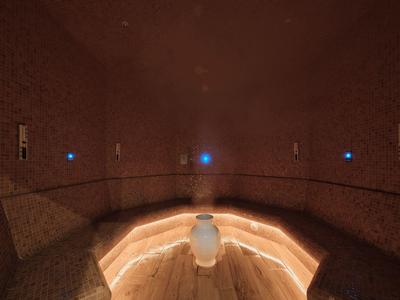 Ciemne pomieszczenie wellness z pośrednim oświetleniem LED i powierzchniami granitowymi.