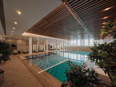 Nowoczesny basen kryty ze drewnianym sufitem i roślinami dekoracyjnymi.